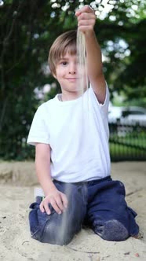 Boy is Playing in Sandpit Playground Under the Sun A Little Boy Sits in a Sandbox in the Yard and