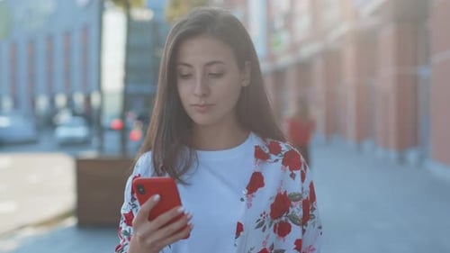 Pretty Female Tourist Busy Typing Message on Smartphone Walking in the City Portrait of Caucasian