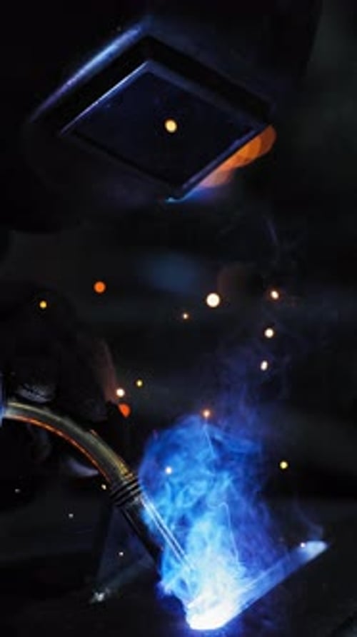 Professional Welder Working at Factory Facility Factory Workshop with a Male Technician Welding in