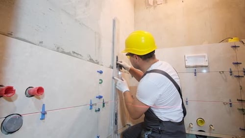 Tradesman Carefully Installs Tile in Bathroom