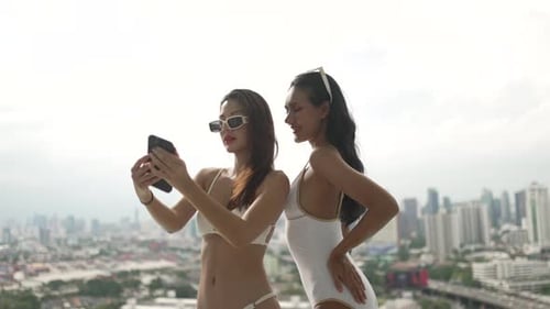 Female friends spend leisure activity at rooftop swimming pool.