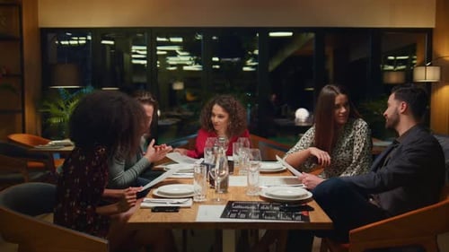 Diverse Group Sitting Restaurant Table at Night. Happy Friends Going Out Together