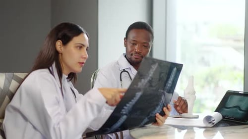 Two diverse doctors collaborate in a hospital, examining test results and discussing X-ray scans
