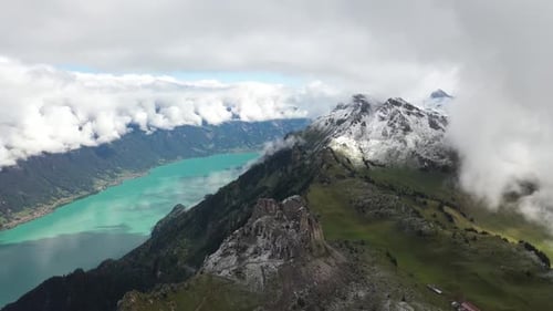 Drone shot of a massive and colorful river running between two epic mountains with forest, grass, gr