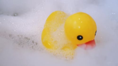 One yellow rubber duck with soap bubble bath, light background with bubbles. Kids spa concept. Child