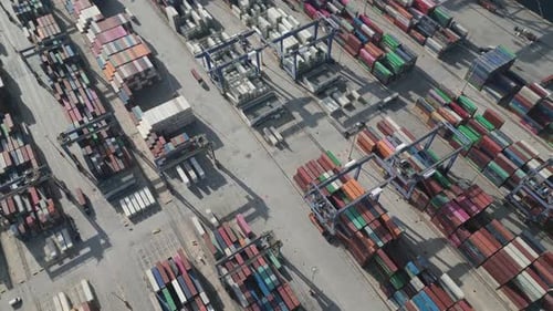 Aerial View of a Container Terminal with Cranes and Trucks in Action