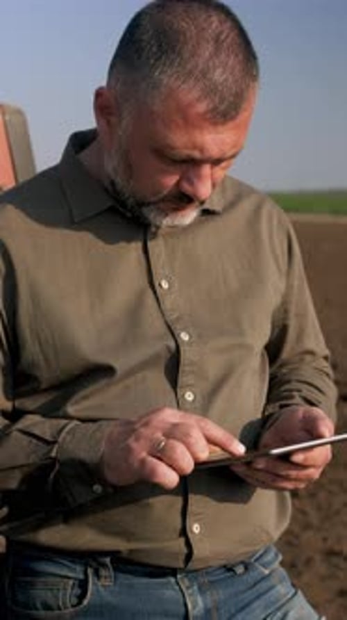 Framer using tablet while standing in field.