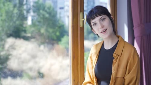 Young Woman Smiles in Front of a Window