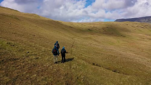 Aerial view of hikers on grassy hill, Faroe Islands.