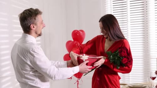 Romantic Man Giving Gift to Woman with Roses