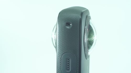 Eine Nahaufnahme einer 360-Kamera mit Doppellinse, zwei Objektivdeckeln, glänzendem Studiolicht, reflektierend, o