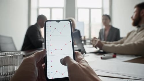 POV of Man Looking at Smartphone Screen during Meeting in Office