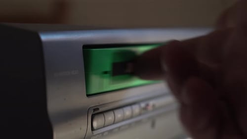 Loading VHS Videotape in Vintage Player, Pressing Play for Playback, Close Up