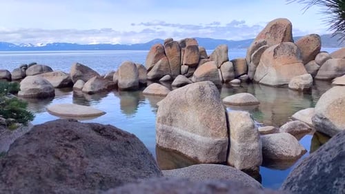 Calming nature background video in HD. Rocks surrounding a pool of crystal clear lake water with sno