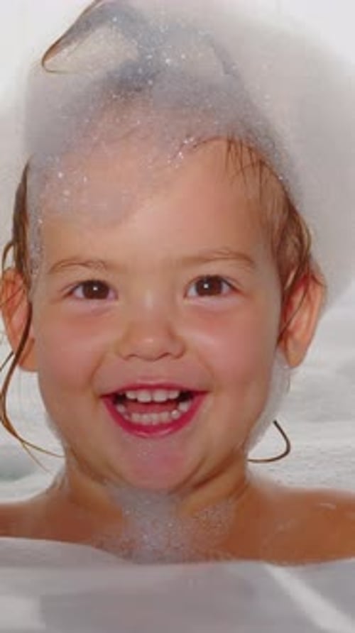 Happy Child Smiles Covered in Bubbles in Bathtub