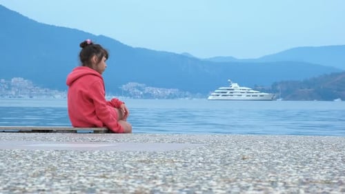 Girl Sitting on Pier Watching Yacht on Sea