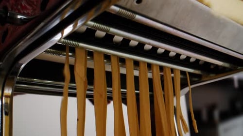 Woman Using Pasta Machine to Make Fresh Pasta Dough in the Kitchen Cooking in Italian Restaurant