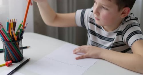 Child Drawing with Colored Pencils at Table Indoors