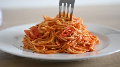 Twisting spaghetti with fork over plate.