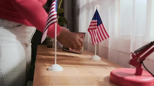 Hands Placing American Flags on Table Indoors