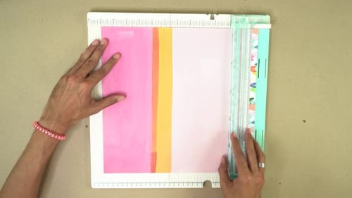 Hands Cutting Colorful Paper with Paper Cutter