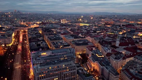 aerial landscape drone shot panning left over Vienna cityscape at night with illuminated streets