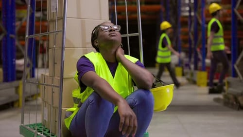 Tired female worker resting in warehouse