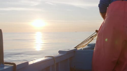 Fischer auf dem Boot in der Morgendämmerung mit Sonnenaufgang über dem Meer