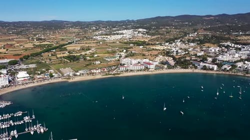 Aerial drone footage of a beach in the village of Sant Antoni on the island of Ibiza in Spain