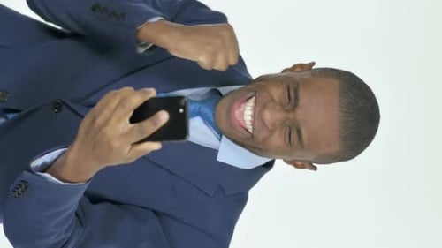 Enthusiastic Man Celebrates Using Smartphone in Studio
