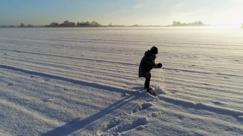 Little boy playing in the snow on big field