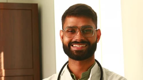 Portrait of Male Indian Doctor Wearing White Coat in Clinic Office
