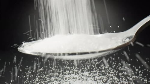 White Sugar Pours Onto Spoon in Close-up