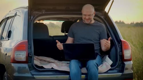 Smiling Man Remote Working on Laptop Computer Talking on Business Online Meeting Sitting in Car