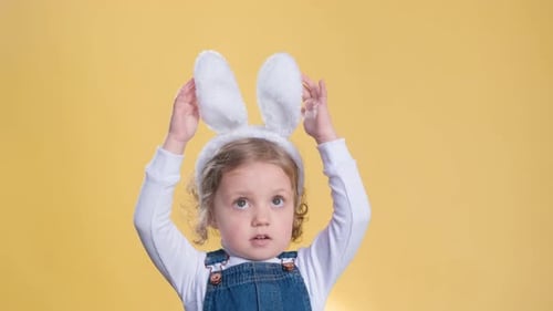 Smiling Child Wearing Bunny Ears on Yellow Background