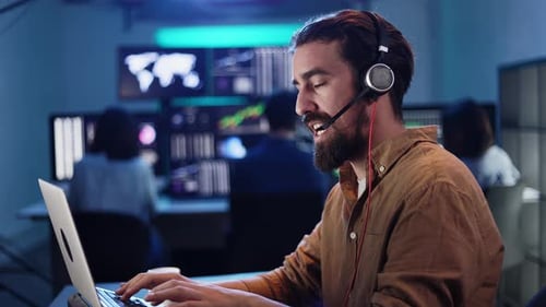 Stock Trader Working on a Laptop in a Busy Office at Night