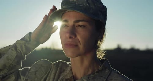 Cinematic Close Up Portrait of Young Female Patriotic Soldier Putting Her Cap on and Saluting in an