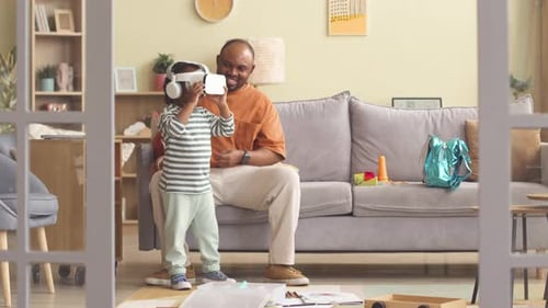Child Uses VR Headset with Adult in Living Room
