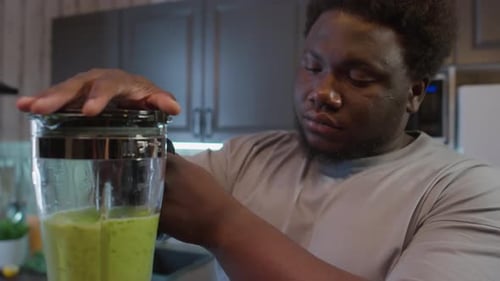 Young Adult Preparing Green Smoothie in a Blender