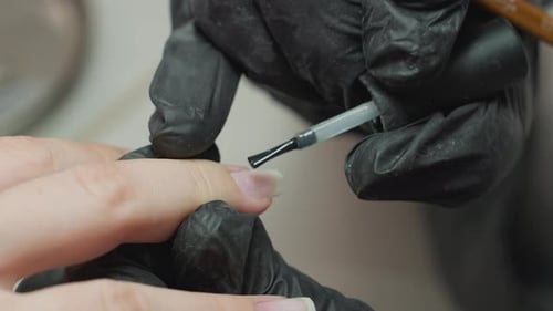 Close Up Nail Hardener Application By Technician in Dusty Gloves