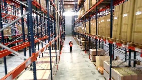 Logistics warehouse worker walking through aisles