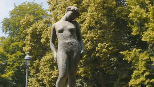 A beautiful capture of a bronze statue depicting a naked woman instead a park.