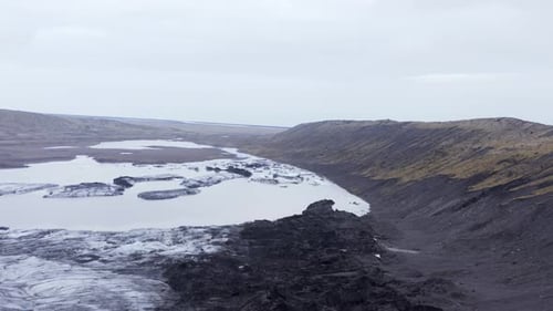 Cloudy weather at KvĂarjökull glacier edge with glacial lagoon, aerial