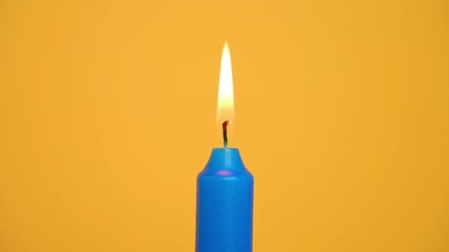 Vela azul acesa sobre fundo amarelo