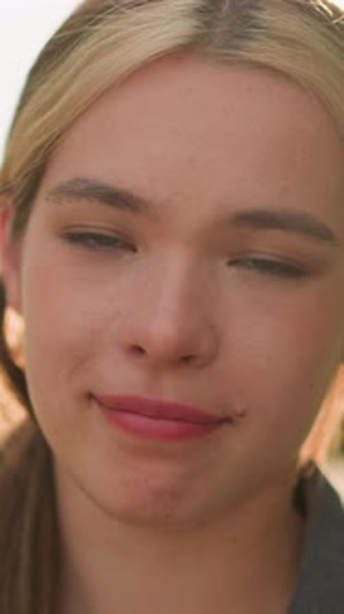 Gros plan d'une femme souriante en plein soleil regardant la caméra