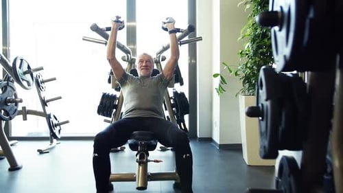 Senior man strengthening upper body doing slow motion workout in gym