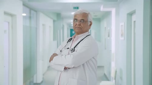 Confident Doctor Stands in Hospital Hallway