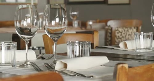 A waiter sets the table in a restaurant before customers arrive, and uses fine cutlery and glasses