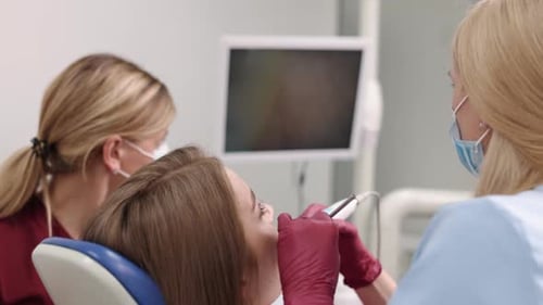 Dentist Examining Patient with Assistant Present