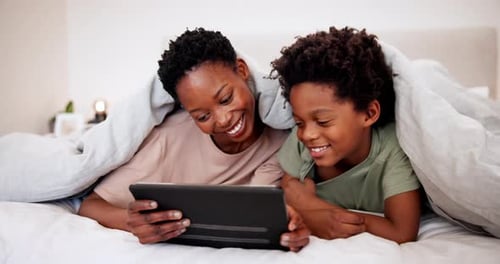 Mother and Child Enjoy Tablet Under Blanket in Bed